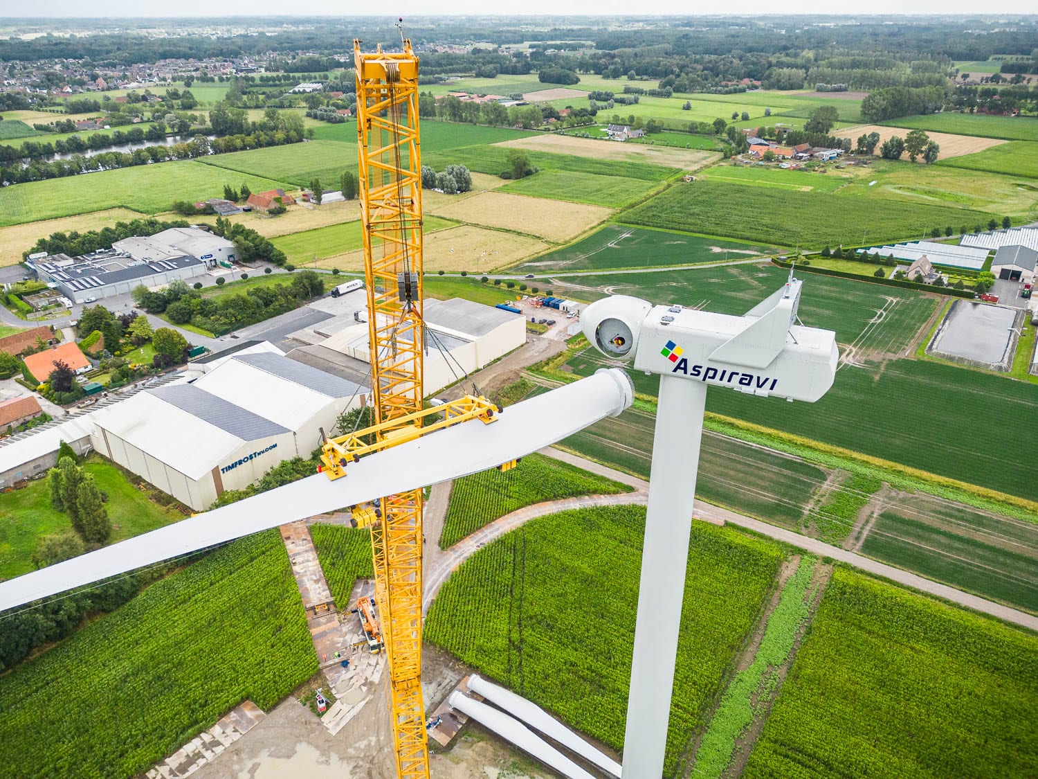 Bouw van een Aspiravi-windturbine, met de zonnepanelen op de Timfrost-gebouwen zichtbaar op de achtergrond